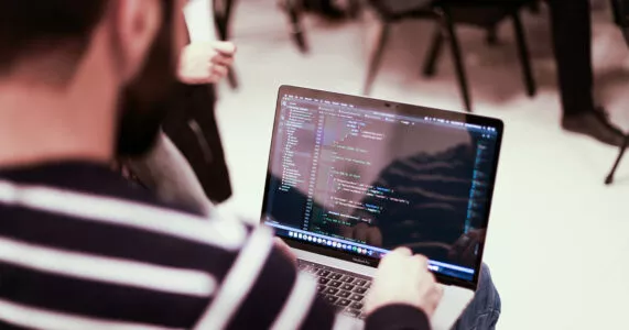 A man using a laptop to write code